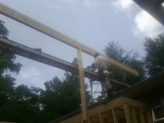 Carpenter setting a ridge beam over a new addition frame — Ice Dam Removal by Roofing Brothers in Kilgore