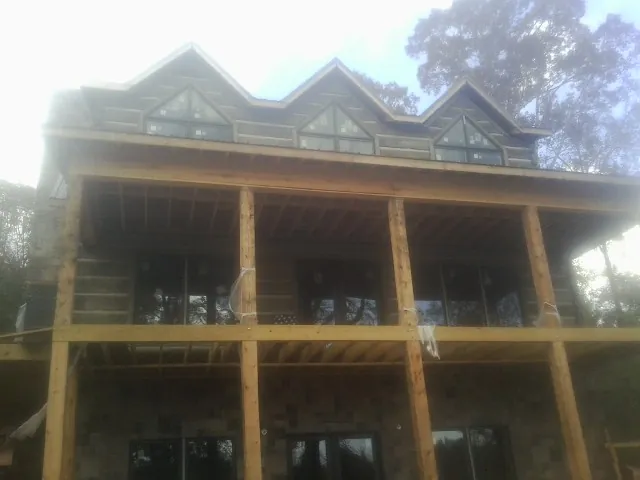 Dormers and porch framing on a large log home under construction — Roof Coating work by our crew in Kilgore