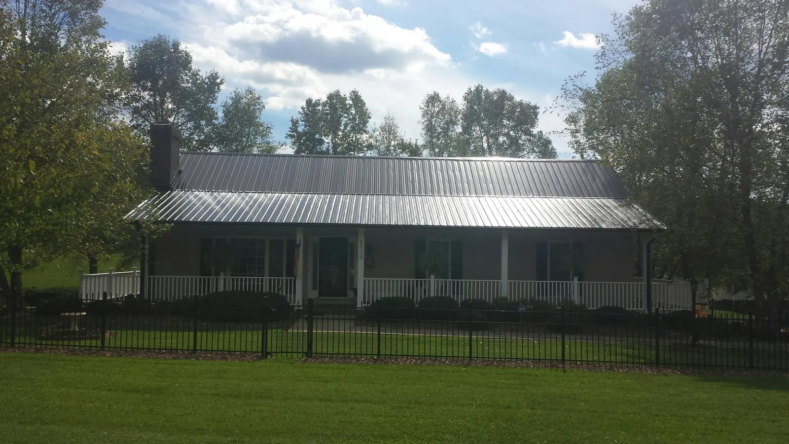 Gray metal roof on a brick ranch with a full width front porch — Gutter Guard Installation work by our crew in Kilgore