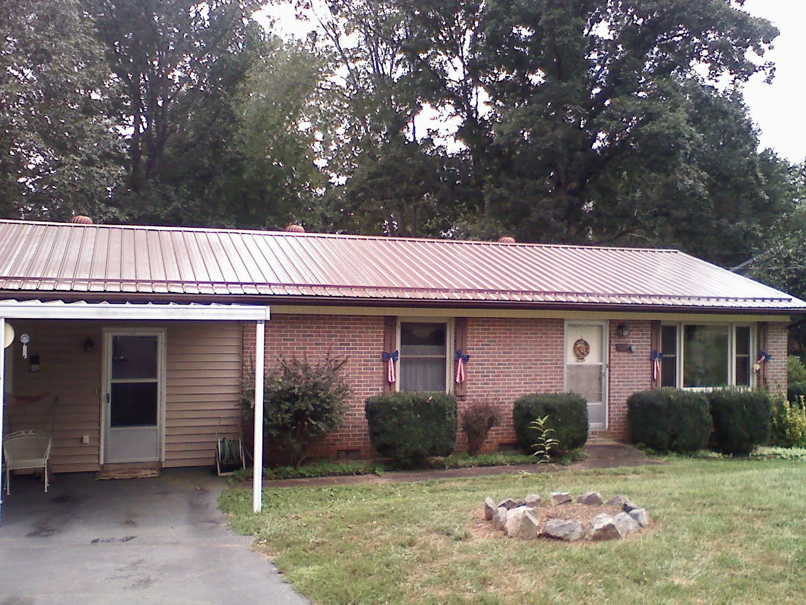 Bronze metal roof and carport on a brick ranch home — Roof Repair work by our crew in Kilgore
