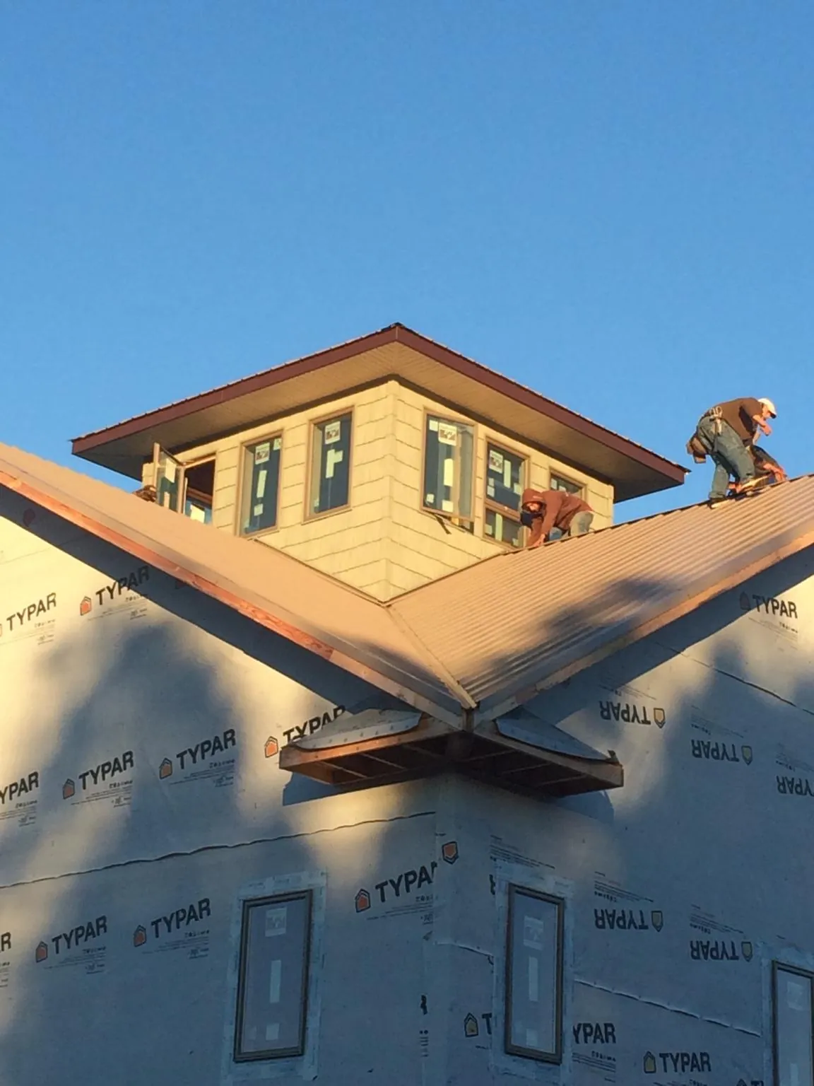 Roofers working around a rooftop cupola on a new metal roof at sunset — Roof Waterproofing in Kilgore by Roofing Brothers